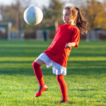 Girl kicks a soccer ball on a soccer field Girl kicks a soccer ball on a soccer field